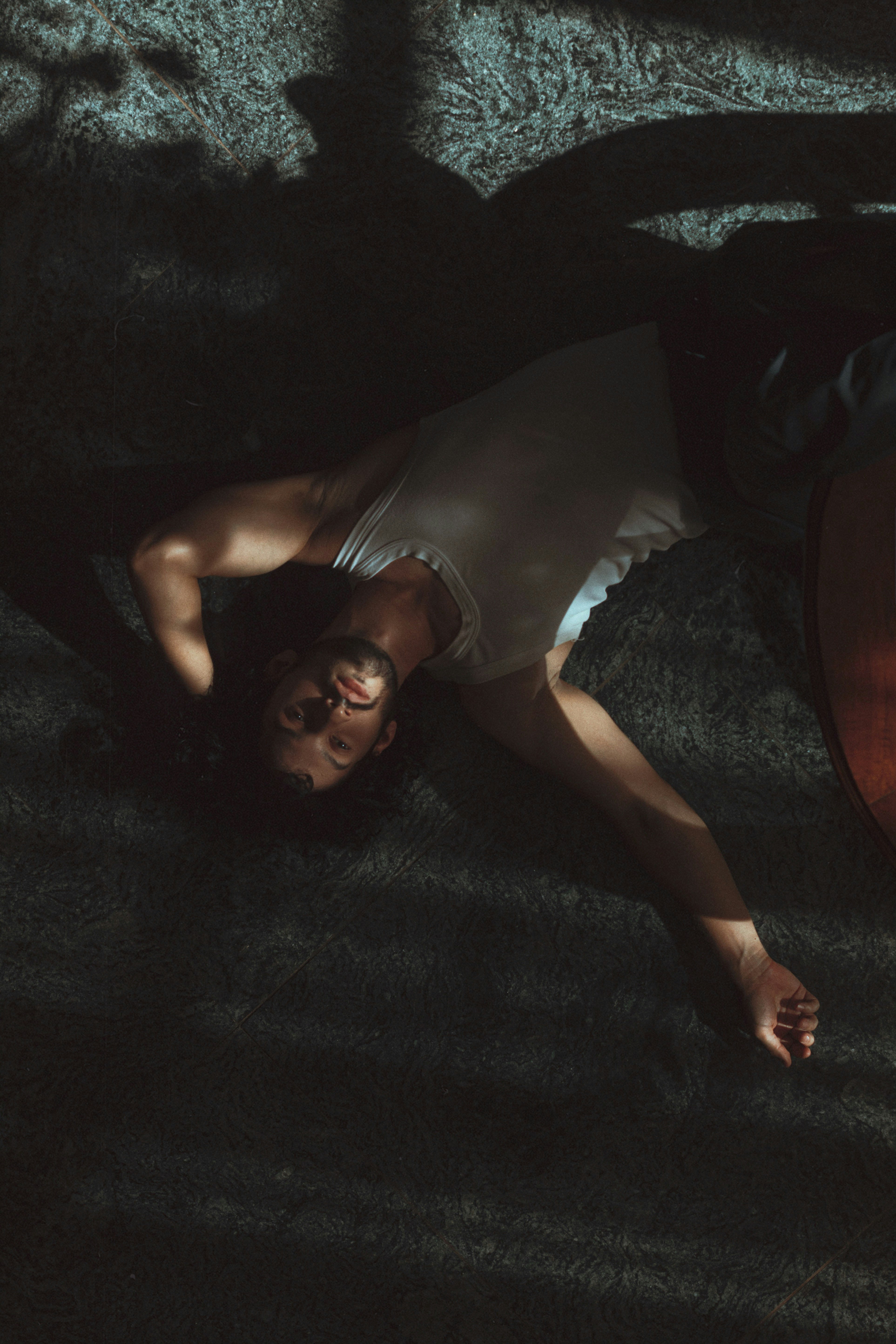 woman in gray tank top lying on black floor